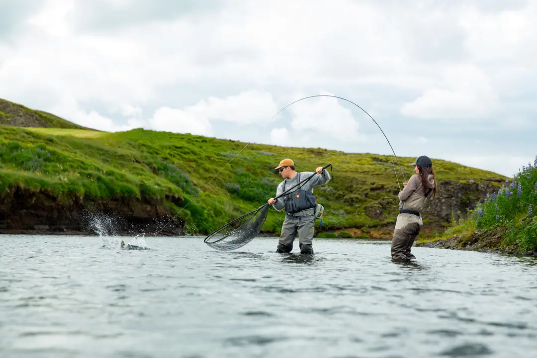 Two anglers on the lower beat, one netting a fish