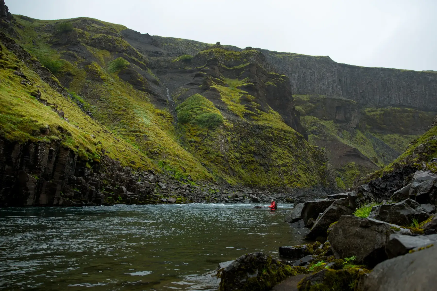 Two anglers on the canyon rim above a waterfall pool