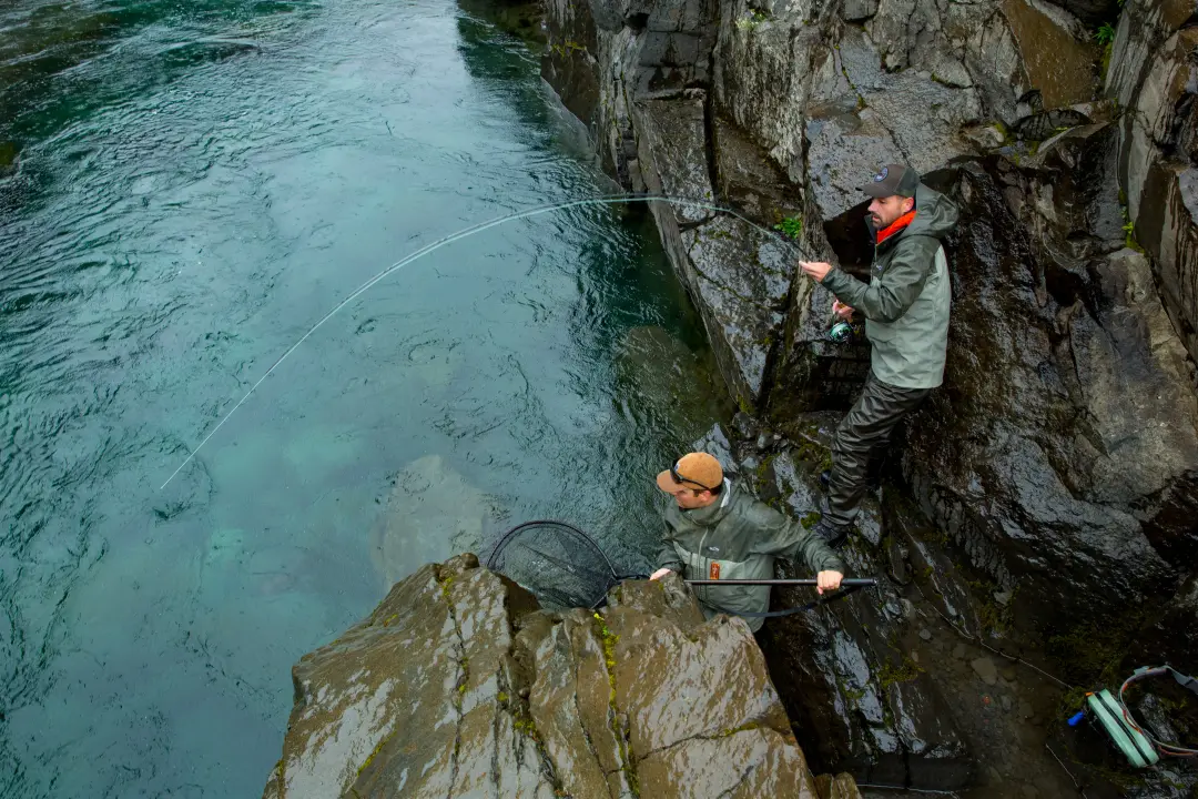 Two anglers netting a fish over the clear water of the upper beat
